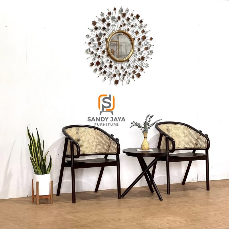 Set 2 kursi teras kayu warna gelap dengan sandaran anyaman rotan alami dan satu meja bulat berdesain kaki silang dari Sandy Jaya Furniture.