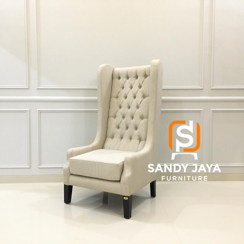 Kursi wingback tinggi warna cream dengan sandaran tufted dan kaki gelap Sandy Jaya Furniture tampak serong